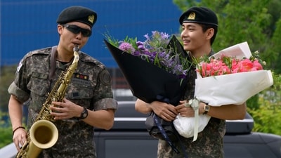 TOPSHOT - K-pop boy band BTS members RM (L) plays the saxophone while V looks on while holding flower bouquets at an outdoor sporting facility in Chuncheon on June 10, 2025, after their release from 18 months of South Korean military service. Hundreds of fans gathered near two army bases just outside of the capital Seoul where band leader RM -- recently named "Favorite K-pop Artist" at the American Music Awards -- and singer V were discharged. (AFP) TOPSHOT - K-pop boy band BTS members RM (L) plays the saxophone while V looks on while holding flower bouquets at an outdoor sporting facility in Chuncheon on June 10, 2025, after their release from 18 months of South Korean military service. Hundreds of fans gathered near two army bases just outside of the capital Seoul where band leader RM -- recently named "Favorite K-pop Artist" at the American Music Awards -- and singer V were discharged. (AFP)