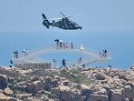 Tourists look on as a Chinese military helicopter flies past Pingtan island, one of mainland China's closest point from Taiwan, in Fujian province on August 4, 2022, ahead of massive military drills off Taiwan following US House Speaker Nancy Pelosi's visit to the self-ruled island. China is due on August 4 to kick off its largest-ever military exercises encircling Taiwan, in a show of force straddling vital international shipping lanes following a visit to the self-ruled island by US House Speaker Nancy Pelosi. Tourists look on as a Chinese military helicopter flies past Pingtan island, one of mainland China's closest point from Taiwan, in Fujian province on August 4, 2022, ahead of massive military drills off Taiwan following US House Speaker Nancy Pelosi's visit to the self-ruled island. China is due on August 4 to kick off its largest-ever military exercises encircling Taiwan, in a show of force straddling vital international shipping lanes following a visit to the self-ruled island by US House Speaker Nancy Pelosi. 