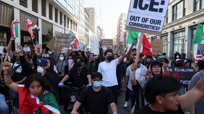 Demonstrators hold signs and flags during a protest against federal immigration sweeps in downtown Los Angeles (REUTERS)