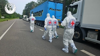 International Red Cross representatives walking past the motorcade of refrigerators of the convoy carrying bodies of Ukrainian soldiers killed in the war with Russia. (AFP/ Coordinating Headquarters for the Treatment of Prisoners of War) International Red Cross representatives walking past the motorcade of refrigerators of the convoy carrying bodies of Ukrainian soldiers killed in the war with Russia. (AFP/ Coordinating Headquarters for the Treatment of Prisoners of War)