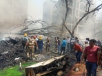 Emergency personnel and other people gather near damaged property at the site where an Air India plane crashed in Ahmedabad on June 12, 2025. 
