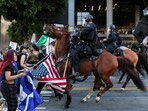 Mounted law enforcement officers confront demonstrators, as they march through downtown as part of the ongoing protests against Immigration and Customs Enforcement (ICE).