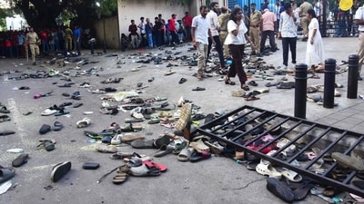 People stand next to abandoned shoes and a fallen barrier following a stampede outside the M Chinnaswamy Stadium in Bengaluru on June 4 (AFP) People stand next to abandoned shoes and a fallen barrier following a stampede outside the M Chinnaswamy Stadium in Bengaluru on June 4 (AFP)