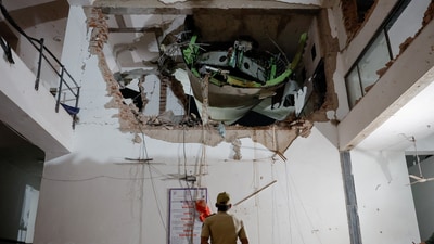 A police officer stands in front of debris at the crash site after an Air India aircraft, bound for London's Gatwick Airport, crashed during take-off from an airport in Ahmedabad. (REUTERS)