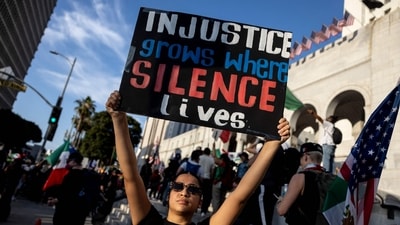 A demonstrator holds a sign reading "Injustice grows where silence lives" in front of City Hall as protests continue in response to federal immigration operations in Los Angeles on June 13, 2025. A judge has ordered Donald Trump to return control of the California National Guard to the state, saying the president's decision to deploy them to protest-hit Los Angeles over Governor Gavin Newsom's objections was "illegal." Protests against Donald Trump's harsh immigration policies spread on June 11 across the United States despite a military-backed crackdown in Los Angeles and threats by the hard-right Republican president to use "heavy force." (Photo by ETIENNE LAURENT / AFP) (AFP) A demonstrator holds a sign reading "Injustice grows where silence lives" in front of City Hall as protests continue in response to federal immigration operations in Los Angeles on June 13, 2025. A judge has ordered Donald Trump to return control of the California National Guard to the state, saying the president's decision to deploy them to protest-hit Los Angeles over Governor Gavin Newsom's objections was "illegal." Protests against Donald Trump's harsh immigration policies spread on June 11 across the United States despite a military-backed crackdown in Los Angeles and threats by the hard-right Republican president to use "heavy force." (Photo by ETIENNE LAURENT / AFP) (AFP)