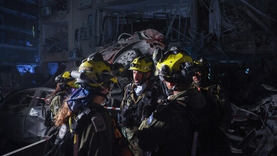 Members of the Israeli security forces inspect a site hit by a missile fired from Iran, in Ramat Gan on the outskirts of Tel Aviv.(Jack Guez/AFP)
