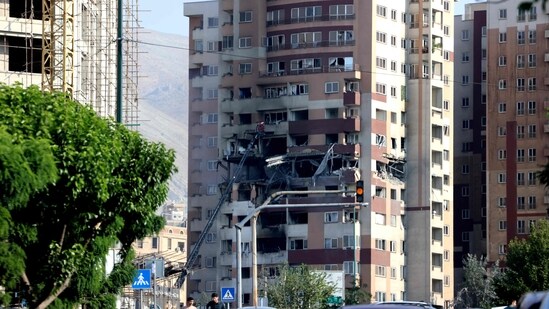 People walk past traffic in front of a building targeted by an Israeli strike in the Iranian capital Tehran.(Atta Kenare/AFP)