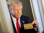 President Donald Trump holds up the $5 million gold card as he speaks to reporters while in flight on board Air Force One. President Donald Trump holds up the $5 million gold card as he speaks to reporters while in flight on board Air Force One.