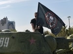 A man mounts a flag of Wagner group on top of an old tank exhibited at the Leninist Komsomol park in Donetsk, Russian-controlled Ukraine, on October 1, 2023, (Photo by STRINGER / AFP)
