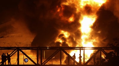 People watch from a bridge as flames from an Israeli attack rise from Sharan Oil depot, following Israeli strikes on Iran, in Tehran. (REUTERS)