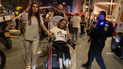 Israelis move an injured Israeli woman to an ambulance near a building hit by a ballistic missile launched from Iran in Bat Yam, Israel, on Sunday (Bloomberg) Israelis move an injured Israeli woman to an ambulance near a building hit by a ballistic missile launched from Iran in Bat Yam, Israel, on Sunday (Bloomberg)