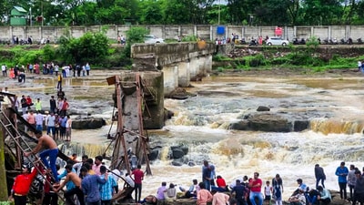 People stand near an iron bridge over the Indrayani river after it collapsed, in Pune district, Maharashtra, Sunday, June 15. (PTI) People stand near an iron bridge over the Indrayani river after it collapsed, in Pune district, Maharashtra, Sunday, June 15. (PTI)