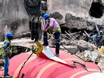 The wreckage of the crashed Air India plane being lifted by a crane from the roof of the BJ Medical College mess building. (HT PHOTO)