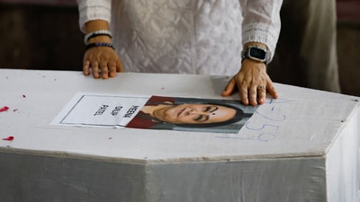 Meena Patel's daughter touches the portrait of her mother, who died in the Air India Boeing 787-8 Dreamliner plane crash during take-off from Ahmedabad airport on June 12 (REUTERS)
