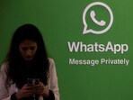 FILE PHOTO: A woman uses her phone next to a logo of the WhatsApp application during Global Fintech Fest in Mumbai.