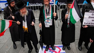 Iran-Israel War: A member of the Neturei Karta, a fringe Jewish group that opposes the state of Israel, stands over a sign with an Israeli flag with a prohibition symbol over it as he and others take part in a protest in support of Iran and Palestinians, at Times Square in New York City. (REUTERS)