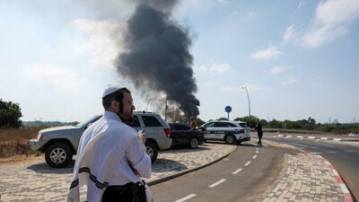 Iran-Israel War: An Israeli man looks on as smoke rises following a missile attack from Iran, in Herzliya on Tuesday. (REUTERS)