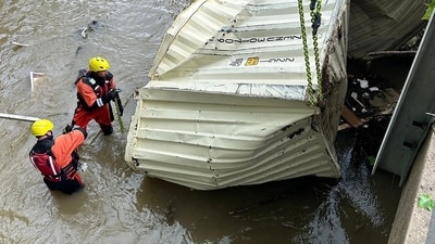 Firefighters removing a crushed container removed from river by Shilling Bridge in the Elm Grove neighborhood of Wheeling, West Virginia.&nbsp; (AFP)