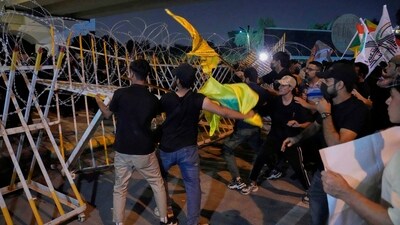 Iran-Israel War: Protesters try to remove barriers set by security forces to close the bridge, leading to the fortified Green Zone where the US Embassy is located, during a protest against Israeli attacks on multiple cities across Iran. (AP) Iran-Israel War: Protesters try to remove barriers set by security forces to close the bridge, leading to the fortified Green Zone where the US Embassy is located, during a protest against Israeli attacks on multiple cities across Iran. (AP)