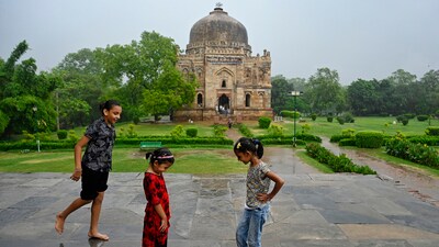 Children enjoy the rain at Bada Gumbad, at Lodhi Garden in New Delhi on Tuesday. (ANI)
