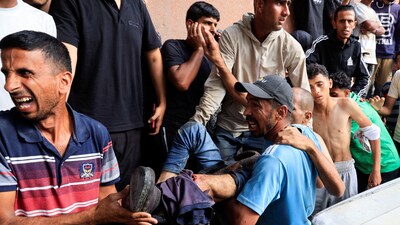 Iran-Israel War: A Palestinian carries a man who was wounded in an Israeli strike while waiting for aid, according to the Gaza Health Ministry, at Nasser hospital, in Khan Younis, southern Gaza Strip on Tuesday. (REUTERS)