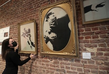 An art handler shows to reporters work "Love Is In The Air" by street artist Banksy, as preparations take place for the exhibition "Banksy, (REUTERS)