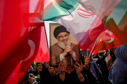 A woman holds a portrait of former Hezbollah leader Sayyed Hassan Nasrallah (AP)