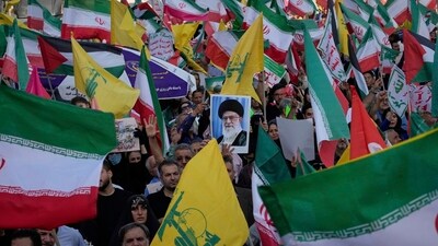 Demonstrators wave Iranian and Hezbollah flags as one holds up a poster of Iran's Supreme Leader Ayatollah Ali Khamenei (AP) Demonstrators wave Iranian and Hezbollah flags as one holds up a poster of Iran's Supreme Leader Ayatollah Ali Khamenei (AP)