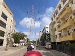 the rider can be seen navigating a stretch of road where an imposing high-tension (HT) transmission tower obstructs the path.
