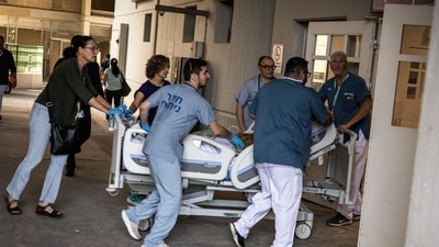 Doctors wheel a patient to safety after a building at Soroka Hospital was struck by an Iranian missile in Beersheba in southern Israel. (AFP) Doctors wheel a patient to safety after a building at Soroka Hospital was struck by an Iranian missile in Beersheba in southern Israel. (AFP)
