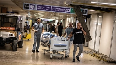 Doctors wheel a patient to safety after a building at Soroka Hospital was struck by an Iranian missile in Beersheba in southern Israel. (AFP) Doctors wheel a patient to safety after a building at Soroka Hospital was struck by an Iranian missile in Beersheba in southern Israel. (AFP)