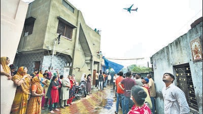 People wait for the funeral procession for Rajendra Patankar, a victim of the June 12 Air India plane crash, as a plane takes off from the airport in Ahmedabad, on Thursday. (AP) People wait for the funeral procession for Rajendra Patankar, a victim of the June 12 Air India plane crash, as a plane takes off from the airport in Ahmedabad, on Thursday. (AP)