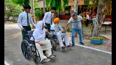 Volunteers helping senior citizens reach their designated polling booths in Ludhiana on Thursday. (Gurpreet Singh/HT)