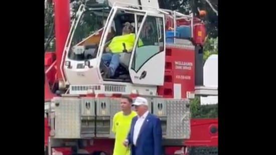 Unaware of the situation behind him, Donald Trump continued chatting with workers and admiring the structures. (X/@_johnnymaga)