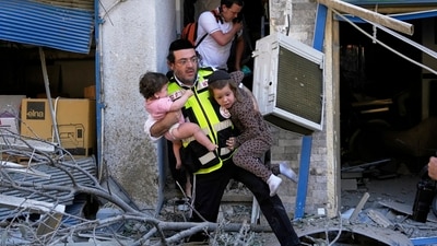 A rescue worker evacuates two children from the site where a missile launched from Iran struck in Haifa, Israel, Sunday, June 22, 2025. (AP) A rescue worker evacuates two children from the site where a missile launched from Iran struck in Haifa, Israel, Sunday, June 22, 2025. (AP)