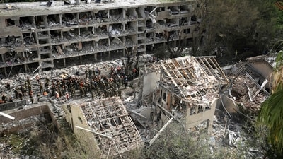 Rescue workers and firefighters survey the site of a direct missile strike launched from Iran in Tel Aviv. (AP)