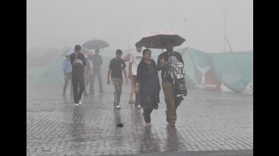 People walking under umbrellas amid rain, on The Ridge in Shimla on Sunday. (Deepak Sansta/HT) People walking under umbrellas amid rain, on The Ridge in Shimla on Sunday. (Deepak Sansta/HT)