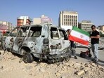 A man holds an Iranian flag by an Iranian Red Crescent ambulance that was destroyed during an Israeli strike, displayed in Tehran on June 23,2025. A man holds an Iranian flag by an Iranian Red Crescent ambulance that was destroyed during an Israeli strike, displayed in Tehran on June 23,2025.