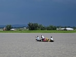 People wade through flood waters on a boat at Lehpati village of Morigaon district in India's northeastern state of Assam on July 3, 2024.  (Photo by Biju BORO / AFP)