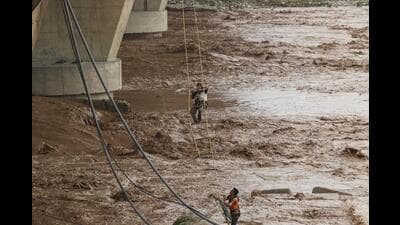 A State Disaster Response Force (SDRF) team member rescuing a man stuck in the middle of the Tawi river following a flash flood after heavy rainfall in Jammu on Wednesday. (PTI Photo) A State Disaster Response Force (SDRF) team member rescuing a man stuck in the middle of the Tawi river following a flash flood after heavy rainfall in Jammu on Wednesday. (PTI Photo)