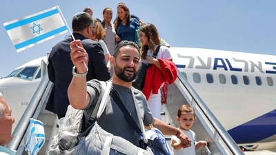 Jewish migrants making Aliyah (immigration to Israel) are handed miniature Israeli flags upon disembarking from an Israeli El Al airlines aircraft after their arrival at Ben Gurion Airport in Lod on June 25, 2025. (AFP) Jewish migrants making Aliyah (immigration to Israel) are handed miniature Israeli flags upon disembarking from an Israeli El Al airlines aircraft after their arrival at Ben Gurion Airport in Lod on June 25, 2025. (AFP)