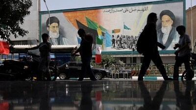 People walk next to a mural with a picture of Iran's Supreme Leader, Ayatollah Ali Khamenei, on a street, early hours of ceasefire, in Tehran, Iran, on June 24. (Reuters) People walk next to a mural with a picture of Iran's Supreme Leader, Ayatollah Ali Khamenei, on a street, early hours of ceasefire, in Tehran, Iran, on June 24. (Reuters)