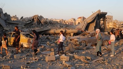 Palestinians walk past the rubble and destroyed vehicles in the Al-Bureij camp in the central Gaza Strip after a house was targeted by an Israeli strike, on June 27, 2025. (AFP) Palestinians walk past the rubble and destroyed vehicles in the Al-Bureij camp in the central Gaza Strip after a house was targeted by an Israeli strike, on June 27, 2025. (AFP)