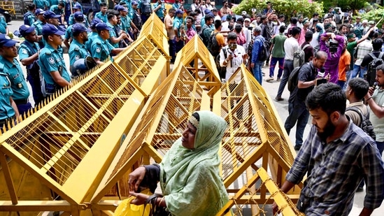 Police personnel stand guard at barricades across a road as protesters march through the streets of Dhaka. (File photo/AFP)