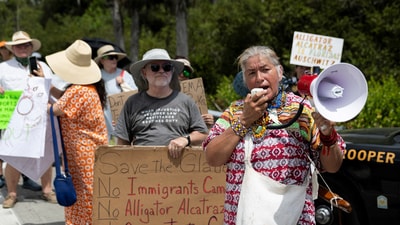 Betty Osceola of the Miccosukee Panther Clan uses a bullhorn as pro-immigrant protesters, environmental groups, Everglades advocates, members of the Miccosukee Native American community and residents gather outside the Dade-Collier Training and Transition Airport as they rally against the state's forthcoming 'Alligator Alcatraz' ICE detention center in Ochopee, Florida (REUTERS)