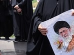 A woman holds a picture of Iran's Supreme Leader Ayatollah Ali Khamenei.