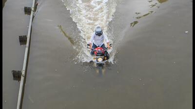 A commuter rides his motorcycle through a waterlogged service road in Gurugram on Tuesday. (PTI)