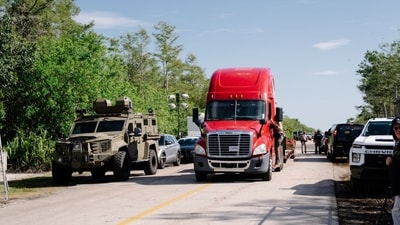 A tractor trailer and law enforcement vehicles at an entrance to Dade-Collier Training and Transition Airport, where a detention center nicknamed "Alligator Alcatraz" is being constructed, in the Everglades near Ochopee, Florida, on Tuesday, July 1, 2025. (Bloomberg)