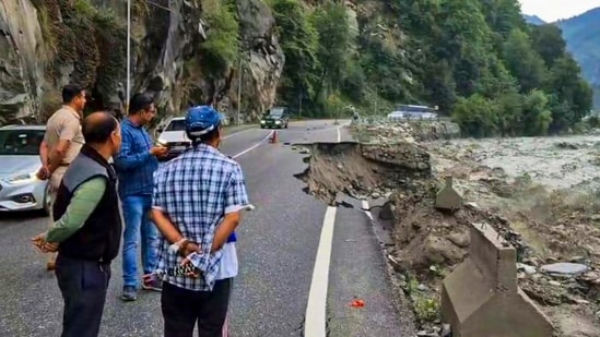 People look at a partially caved in portion of a road, following rainfall at Manali, in Kullu district, Himachal Pradesh. (PTI)