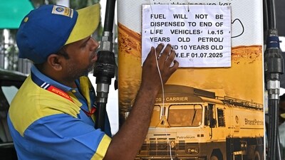 A fuel attendant displays a notice announcing the ban on refuelling petrol cars older than 15 years and diesel vehicles older than 10 years, displayed at a gas station in New Delhi on July 1, 2025. (AFP)